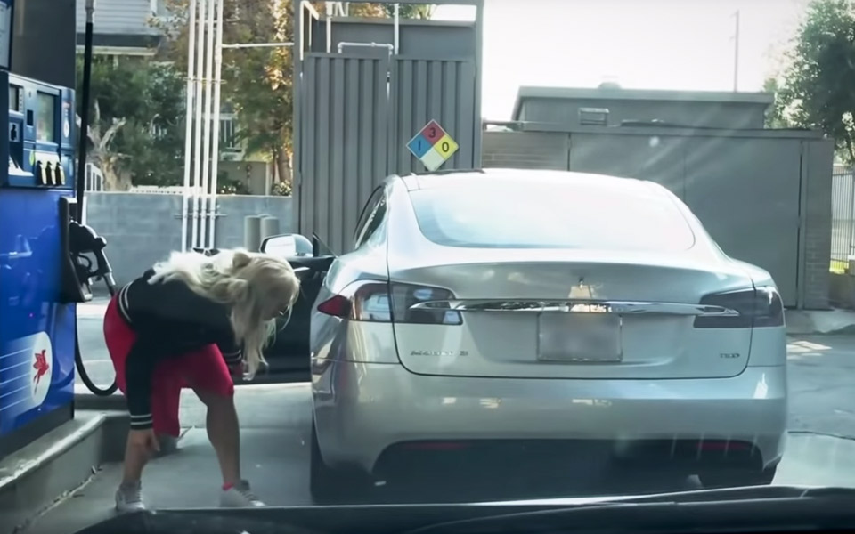 Blondine på tankstationen vil hælde benzin på en Tesla