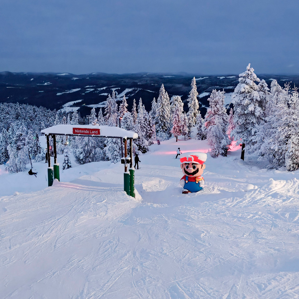 Indgangen til Nintendo Land-pisten i Branäs markeret med et skilt og en Mario-figur på en snedækket bakke.