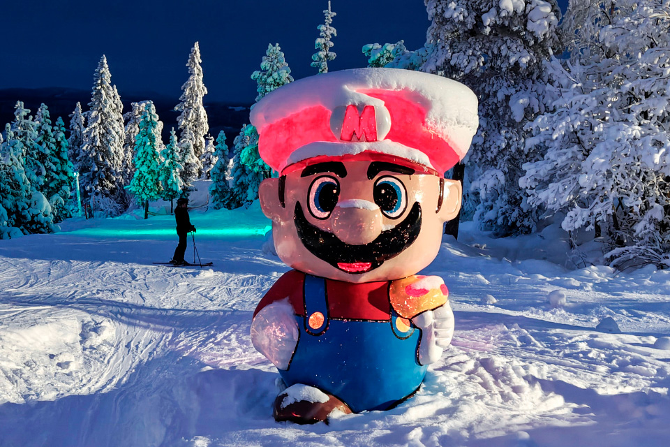 Stor, snedækket Mario-figur ved indgangen til Nintendo Land i Branäs om aftenen.