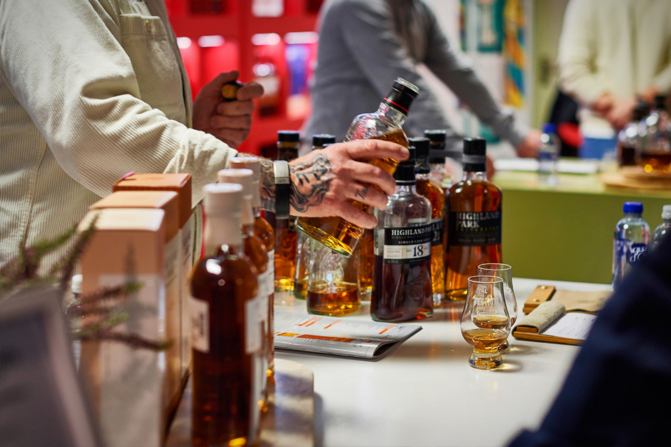 En person med tatovering på hånden hælder whisky op fra en flaske Highland Park 18 år til en smagsprøve.
